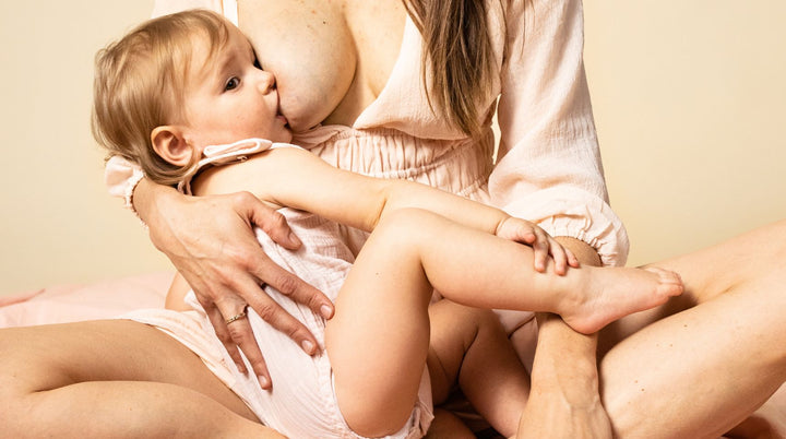 Mom breastfeeding baby on bed