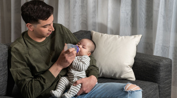 Dad feeding baby expressed breast milk from a bottle.