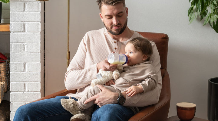 Father feeding baby a bottle of breast milk