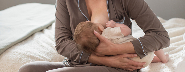 Mom breastfeeding baby on bed