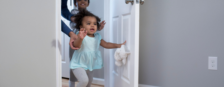 Baby walking through room door in babyproof home